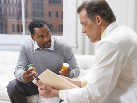 A male patient discusses his hepatitis B treatment office with a physician.