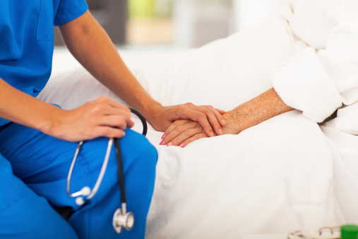 A female liver patient rests after a liver biopsy and is comforted by a female doctor.