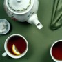 Tumeric tea prepared in a tea pot and served with lemon in a tea cup.