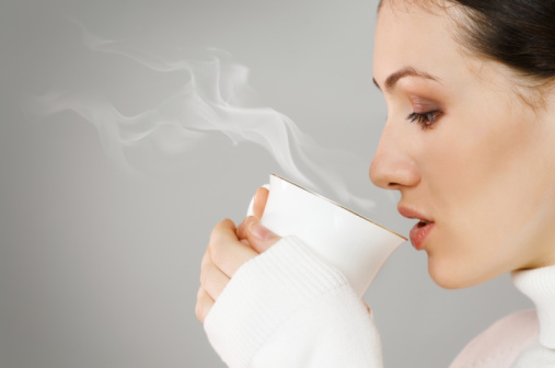 A woman drinks a cup of coffee to prevent liver disease.