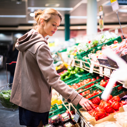 A young woman considers her choices before purchasing produce.