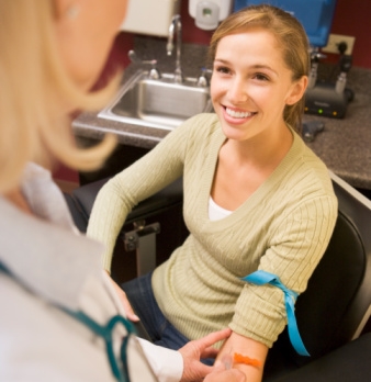 A smiling female patient undergoing a blood test procedure.